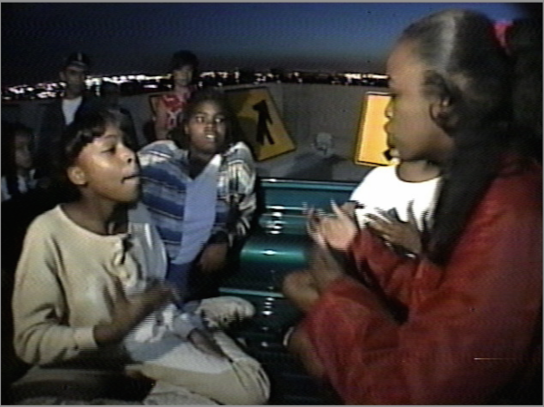 Suzanne Lacy. Still from the making of The Roof Is on Fire, 1992–94. To make this work, a collaborative performance directed by Lacy and documented in photos, videos, and a film, 220 inner-city teens in 100 cars came together on the garage roof of Oakland’s Federal Building to talk openly, with predetermined topics but no script, in front of “eavesdropping” audiences and cameras.